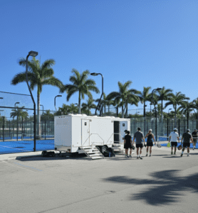 YML luxury portable restroom trailer at padel tennis club with players and palm trees in South Florida